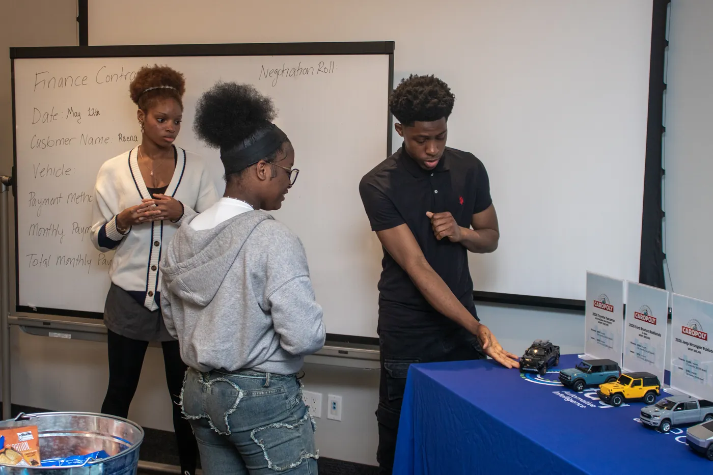 A host speaking with a group of students at taq